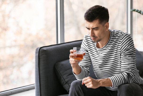Przygnębiony młody człowiek, picie alkoholu w domu - Zdjęcie, obraz