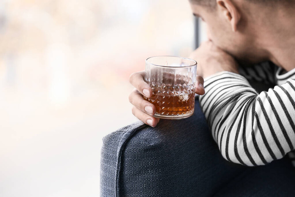 Depressieve jonge man thuis met het drinken van alcohol - Foto, afbeelding