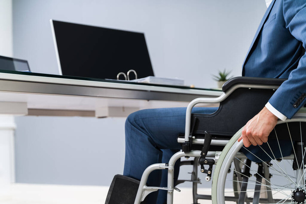 Close-up Of Businessman Sitting On Wheelchair In Office - Zdjęcie, obraz