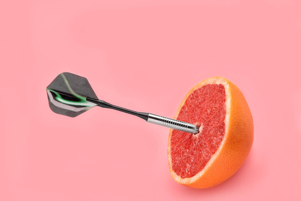 Dart with half of grapefruit on color background - Valokuva, kuva