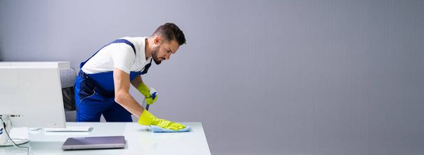 Worker Cleaning Computer Desk With Spray And Sponge - Photo, Image
