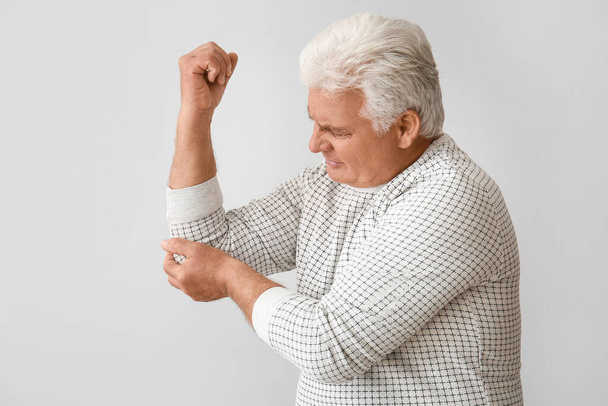 Oudere man met het syndroom van Parkinson op grijze achtergrond - Foto, afbeelding