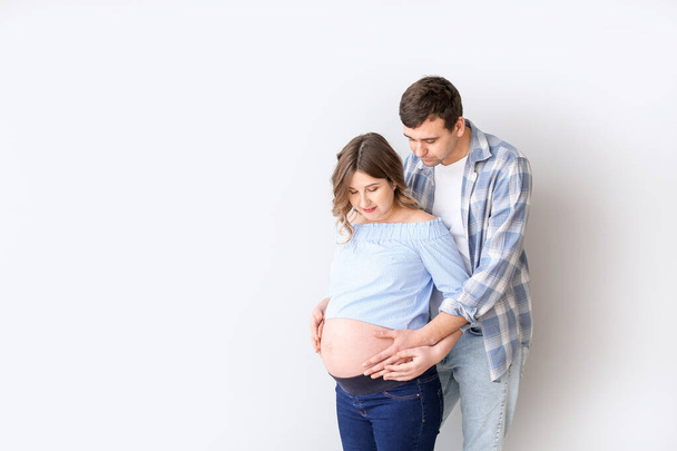 Όμορφη έγκυος ζευγάρι σε γκρι φόντο - Φωτογραφία, εικόνα
