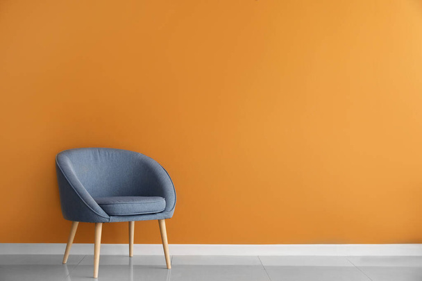 Удобное кресло возле цветной стены - Фото, изображение