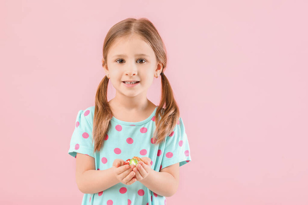 Roztomilá holčička se sladkými čokoládovými vejci na barevném pozadí - Fotografie, Obrázek
