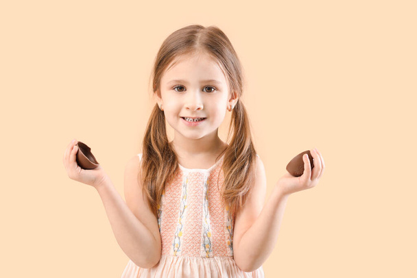 Cute little girl with sweet chocolate egg on color background - Фото, зображення