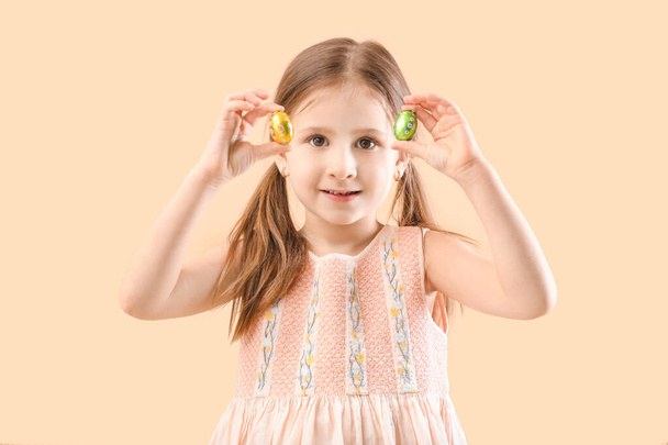 Cute little girl ze słodkimi czekoladowymi jajkami na tle koloru - Zdjęcie, obraz