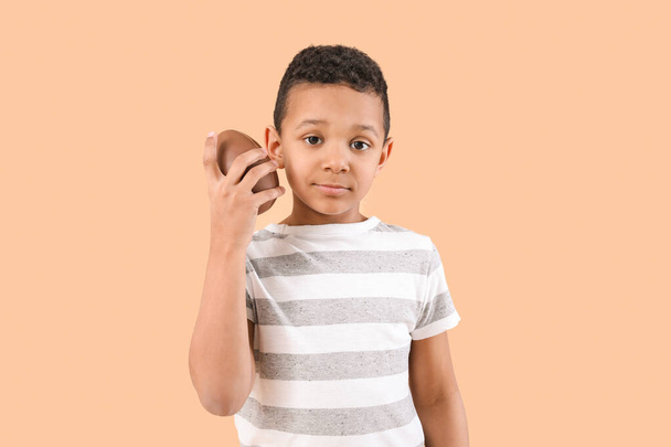 Cute African-American boy with sweet chocolate egg on color background - Fotografie, Obrázek