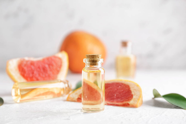Bottles of grapefruit essential oil on table - Foto, afbeelding