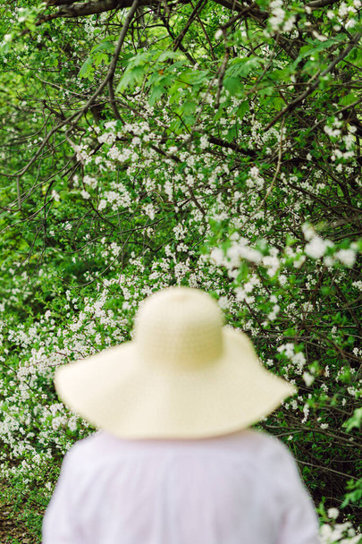 Vrouw met hoed in de tuin, selectieve focus - Foto, afbeelding