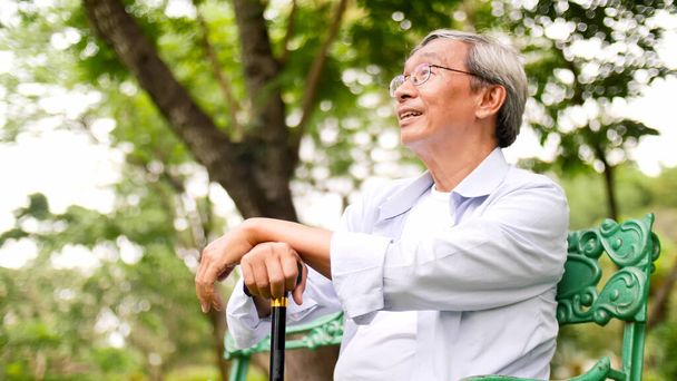 feliz asiático hombre sentado en un banco en el parque
. - Foto, Imagen