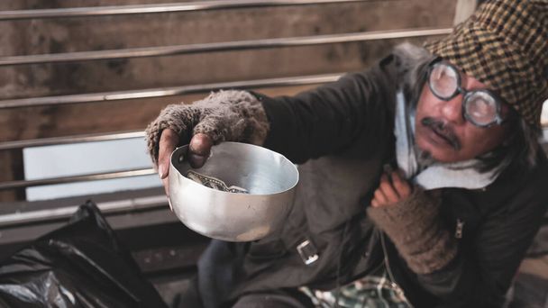 Hombre sin hogar sentado y rogando por dinero
. - Foto, imagen