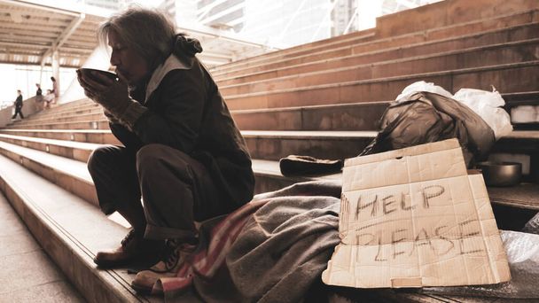 Бездомний чоловік сидить на сходах і їсть їжу
. - Фото, зображення