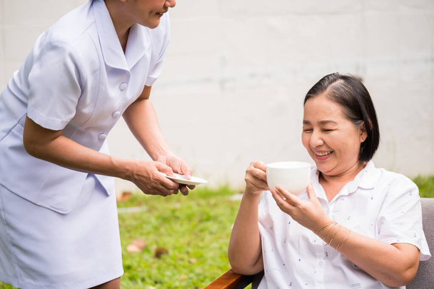 Enfermeira asiática cuidando de paciente feminino no parque hospitalar
 - Foto, Imagem