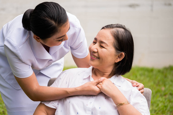 Bela enfermeira cuidando de paciente do sexo feminino no parque hospitalar
 - Foto, Imagem