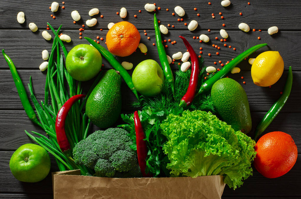 Auf einem schwarzen Holztisch liegt ein Set mit mehrfarbigen Lebensmitteln für eine gesunde Ernährung. - Foto, Bild