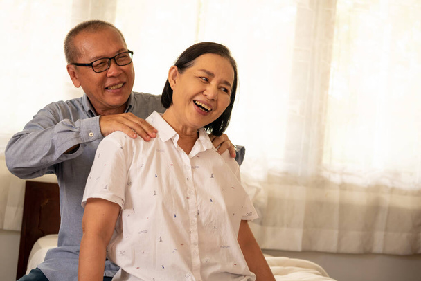 Onnellinen aasialainen aviomies hieroo vaimoaan olkapää talossa
. - Valokuva, kuva
