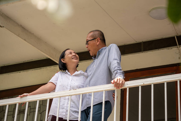 Szczęśliwe azjatyckie pary stojące na balkonie i rozmawiające razem. - Zdjęcie, obraz