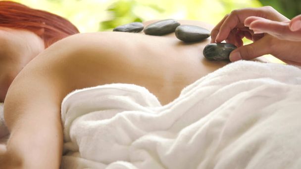 Massage-Therapeut tut Hot Stone Massage für Frau im Spa. - Foto, Bild