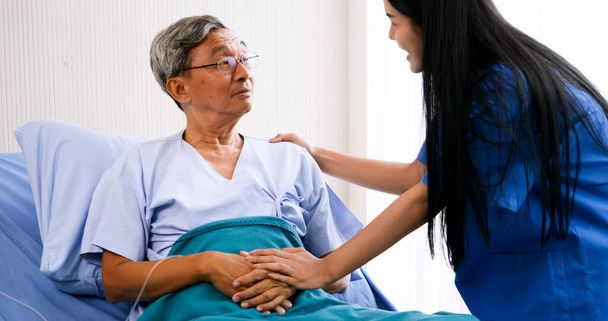 Женщина-ассистент ухаживает за взрослым пациентом в больничной палате
. - Фото, изображение