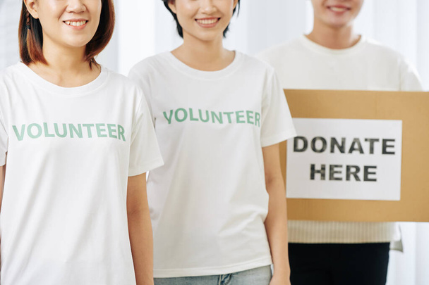 Groep lachende vrijwilligers met kartonnen doos voor donaties - Foto, afbeelding