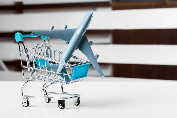 Shopping trolley with toy aircraft on white table close up - 写真・画像