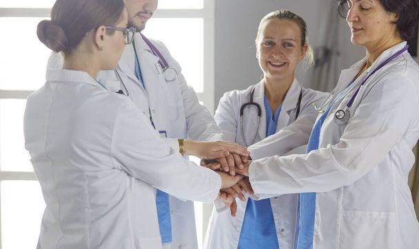 Team of medical workers holding hands together indoors, above view. Unity concept - Photo, Image
