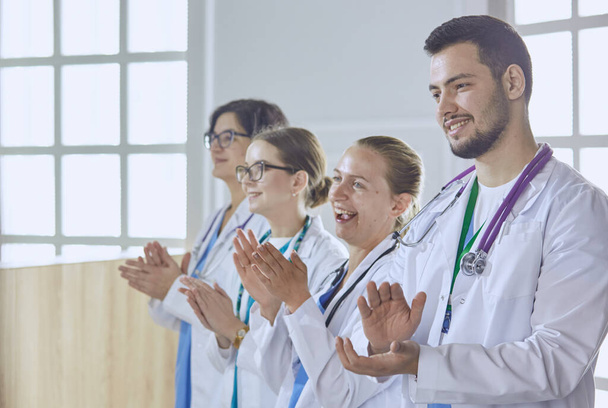 Gelukkig medisch team bestaande uit mannelijke en vrouwelijke artsen brede glimlach en geven een duim omhoog van succes en hoop - Foto, afbeelding
