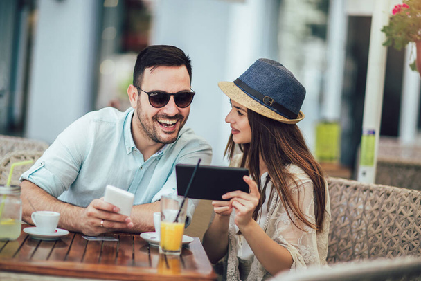 Heureux jeune couple faisant du shopping en ligne assis dans un café
.  - Photo, image