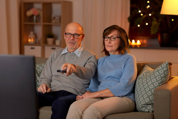 senior couple watching tv at home in evening - Foto, imagen
