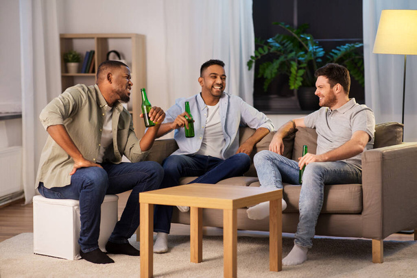 happy male friends drinking beer at home at night - Foto, Bild