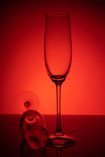 Dos copas vacías de champán con reflejo, sobre fondo rojo y negro degradado. Concepto, fiesta y vida de club. Revista y foto comercial con lugar para texto o diseño, festival
 - Foto, imagen