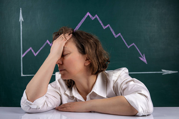 Концепція бізнес-кризи, молода бізнес-леді чіпляється за голову в жаху, на задньому плані графік акцій з негативною тенденцією
. - Фото, зображення