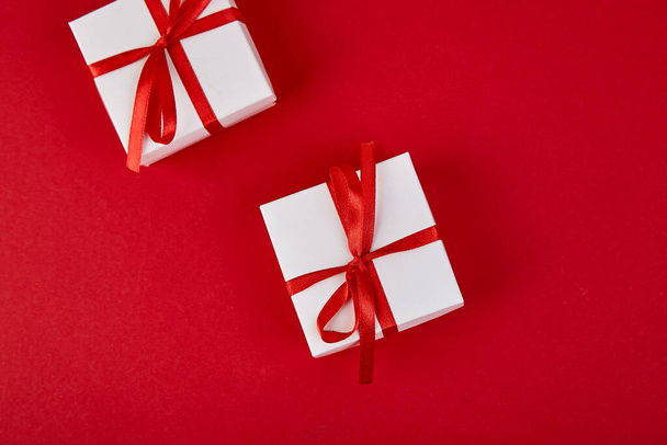 Luxuriöse weiße Geschenkboxen mit rotem Band auf rotem Hintergrund. Valentinstag, Weihnachten, Geburtstagsgeschenke. Mutter- oder Frauentag. Flach lag er. Kopierraum. Ansicht von oben. - Foto, Bild