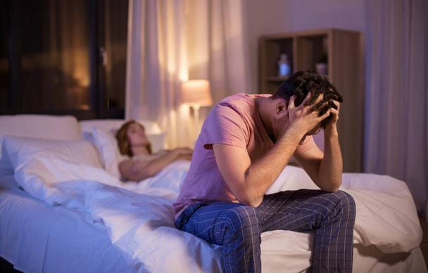 sad man with insomnia sitting on bed at night - Foto, Bild