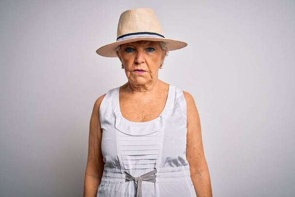 Senior beautiful grey-haired woman on vacation wearing casual summer dress and hat with serious expression on face. Simple and natural looking at the camera. - Foto, Bild