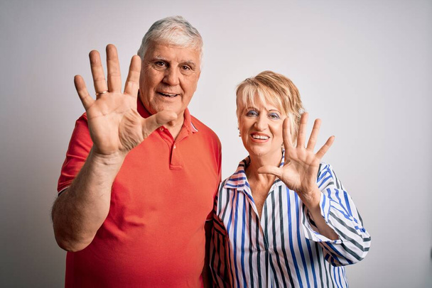 Idősebb szép pár áll együtt felett elszigetelt fehér háttér mutatja, és rámutatva ujjak száma 5 miközben mosolygós magabiztos és boldog. - Fotó, kép