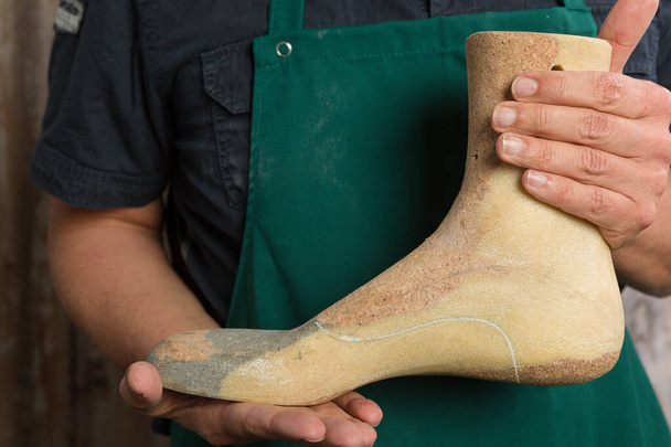 primo piano di mani di calzolaio ortopediche che controllano la qualità di un ultimo di legno
  - Foto, immagini