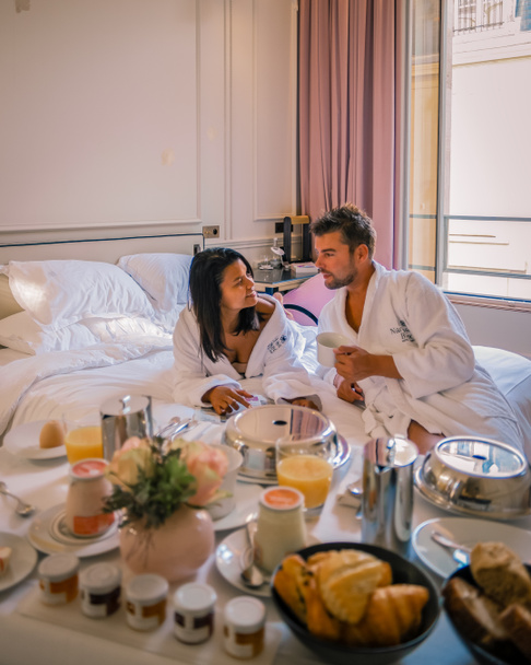 Morning wake up in bed in Paris with breakfast coffee and a newspaper, couple in bed men and woman honymoone valentine couple - Fotografie, Obrázek