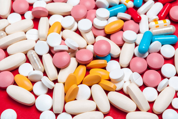 Multicolored pills on red background. Medical concept. Texture. - Φωτογραφία, εικόνα