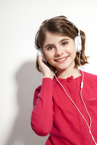 young smiling girl posing in studio while listening music, copy space - Photo, Image