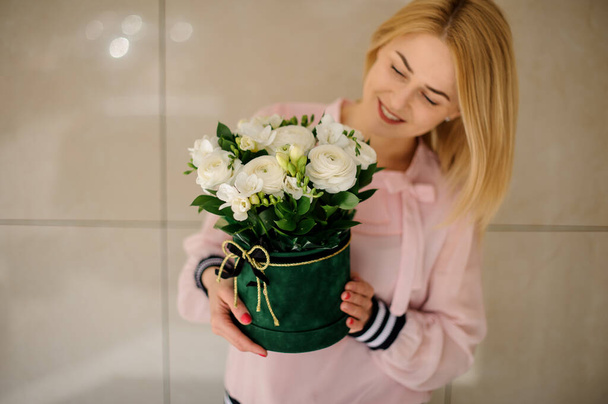 Young woman holding flower composition in round green box in her hands. - Foto, imagen