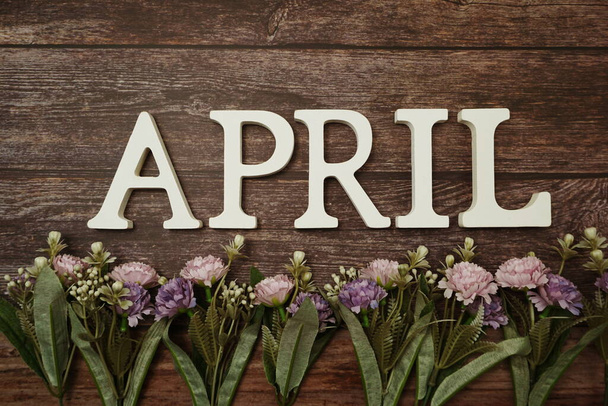 April alphabet letters with flower decoration on wooden background - Photo, Image