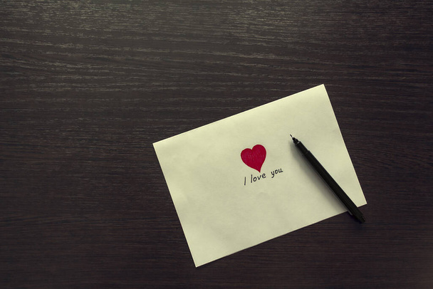Rectangular envelope with a heart and a handle on a wooden table top. Love letter. - Photo, image