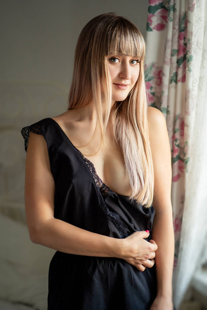 Blonde girl with black lingerie bares breast. - Fotoğraf, Görsel