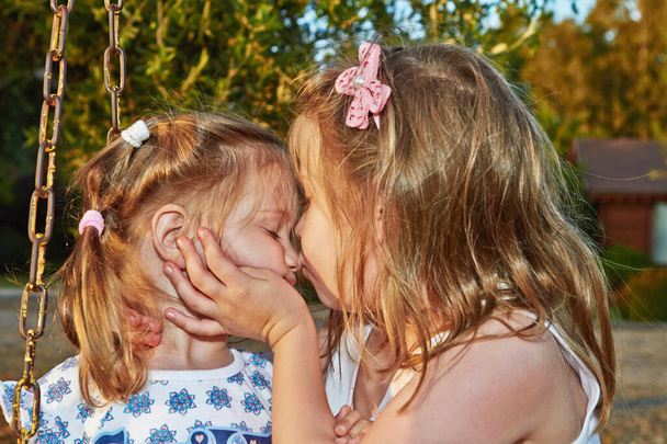 İki tatlı kız, tatlı bir ilişkisi olan küçük kız kardeşler. Kız kardeşler öpüşür. - Fotoğraf, Görsel