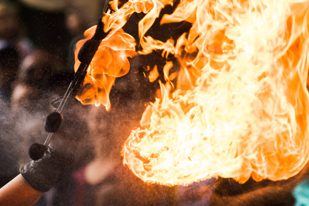 Ένας καλλιτέχνης του Fire show αναπνέει φωτιά στο σκοτεινό λυχνάρι - Φωτογραφία, εικόνα