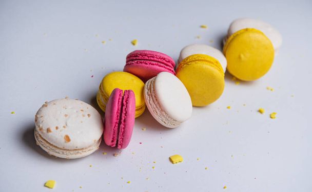 a few delicious colorful  macaron  with crumbs scattered around them are stacked on light gray background.  - Φωτογραφία, εικόνα