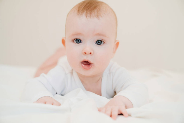 baby in white clothes lying on paunch on bed - Photo, image
