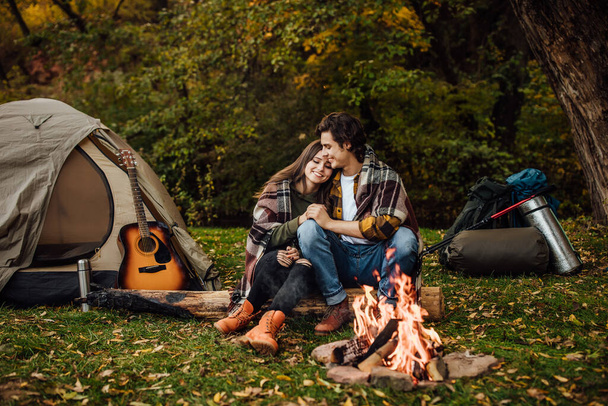 Young loving couple of tourists relaxing near the fire in the nature - Фото, зображення